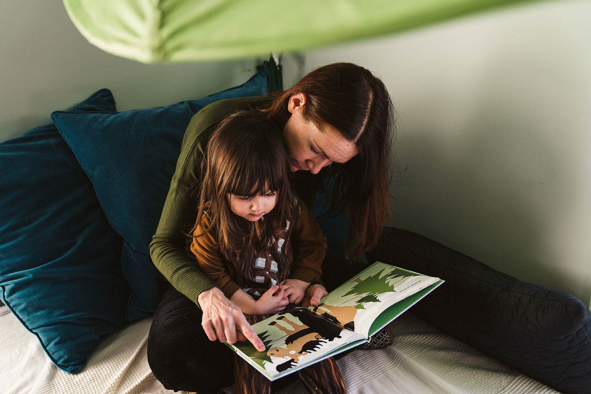 A documentary photograph of mom reading to her daughter during an in home family session in Boston's Jamaica Plain
