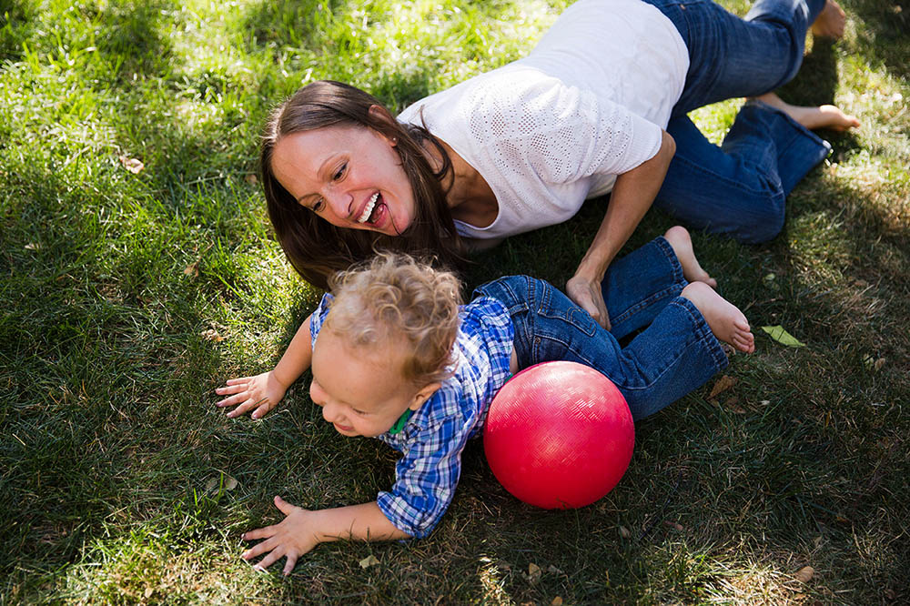A documentary photograph of a mom playing with her son in the backyard during an in home family session in Boston