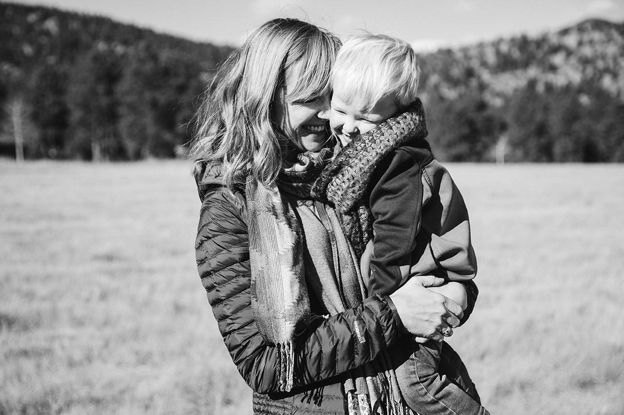 A documentary photograph of a mom holding and snuggling her son during an outdoor family session
