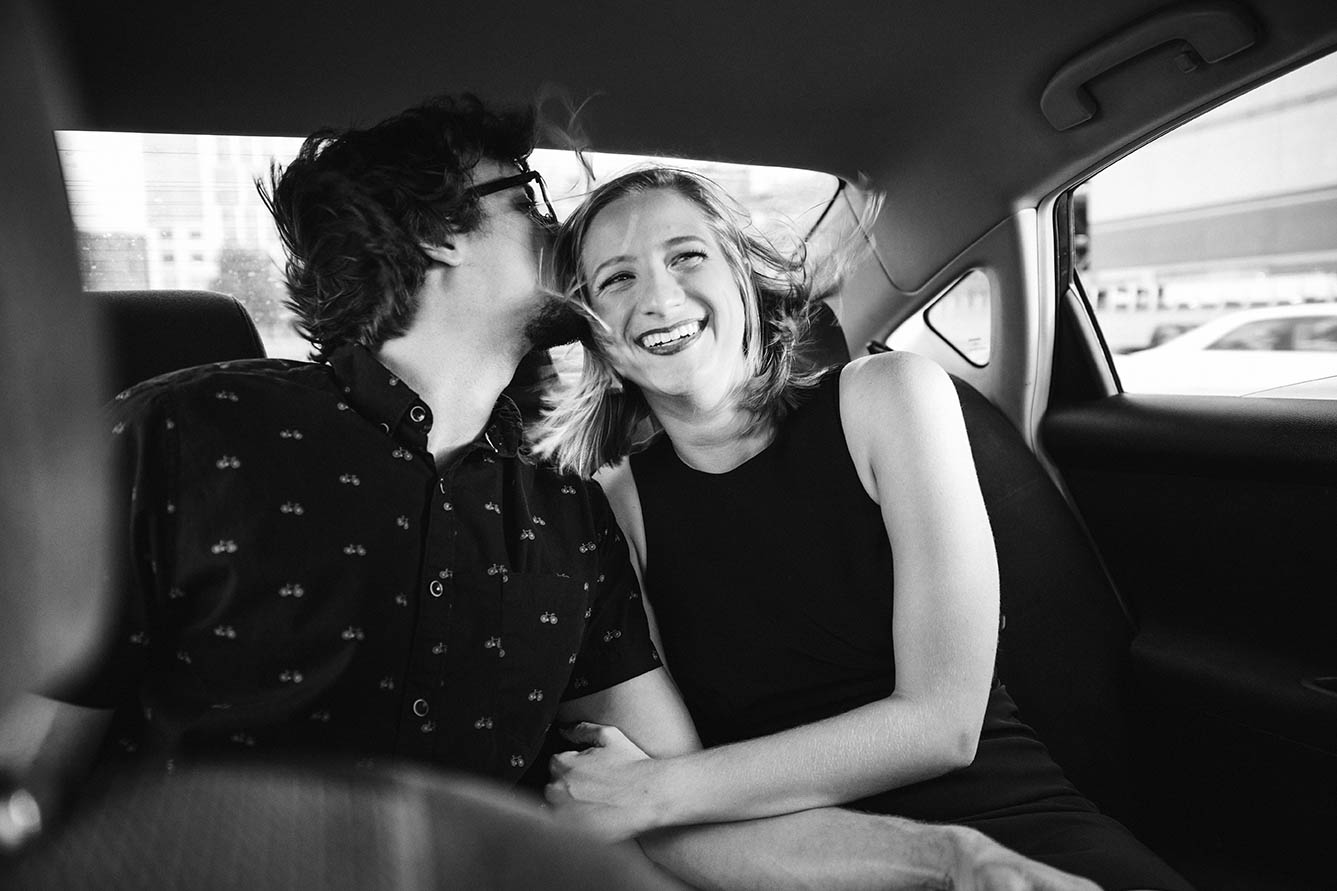 A documentary portrait of a couple snuggling in the back of an Uber during their Boston engagement session