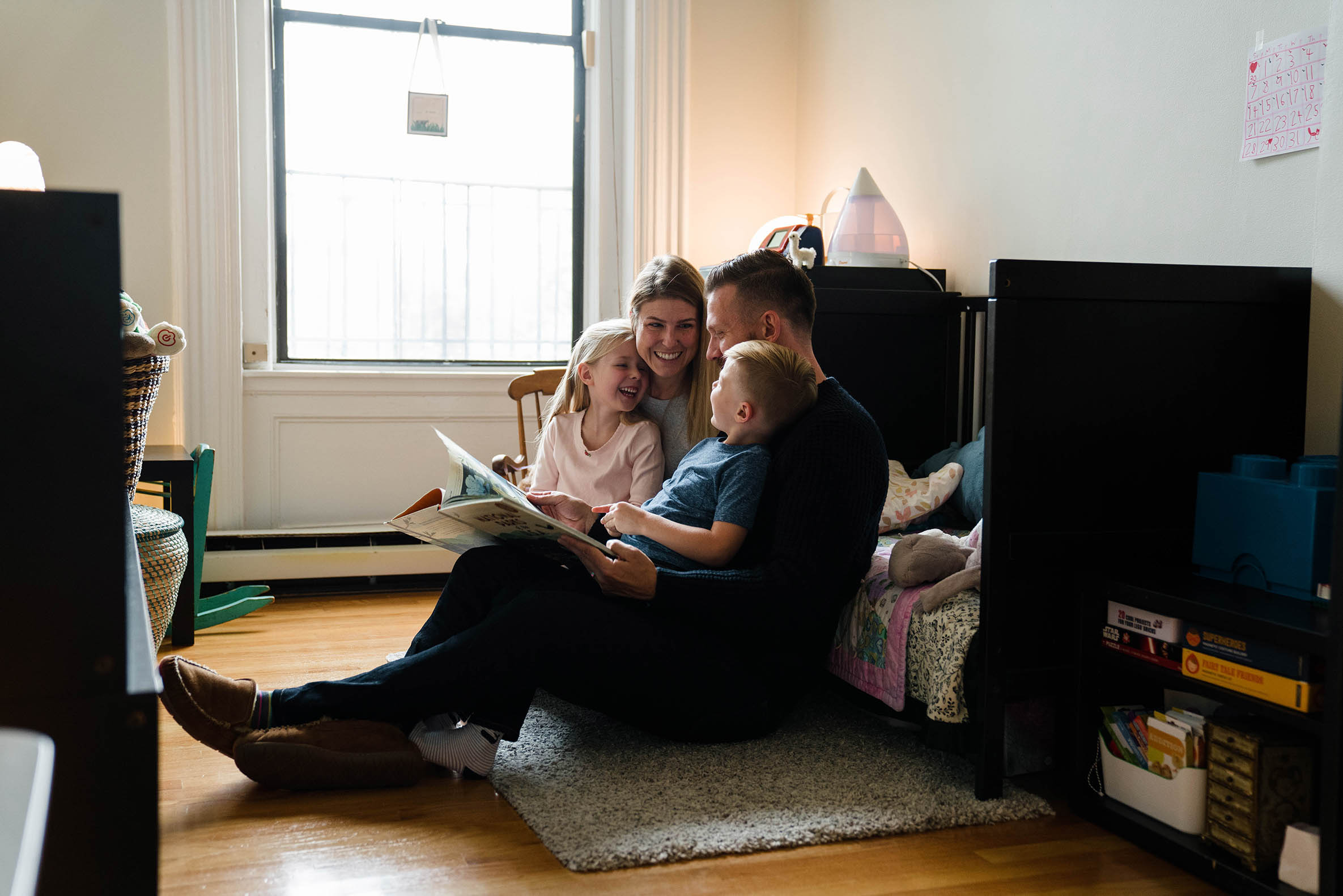 A documentary photograph of a family reading a book together during their in home family session in Boston's South End