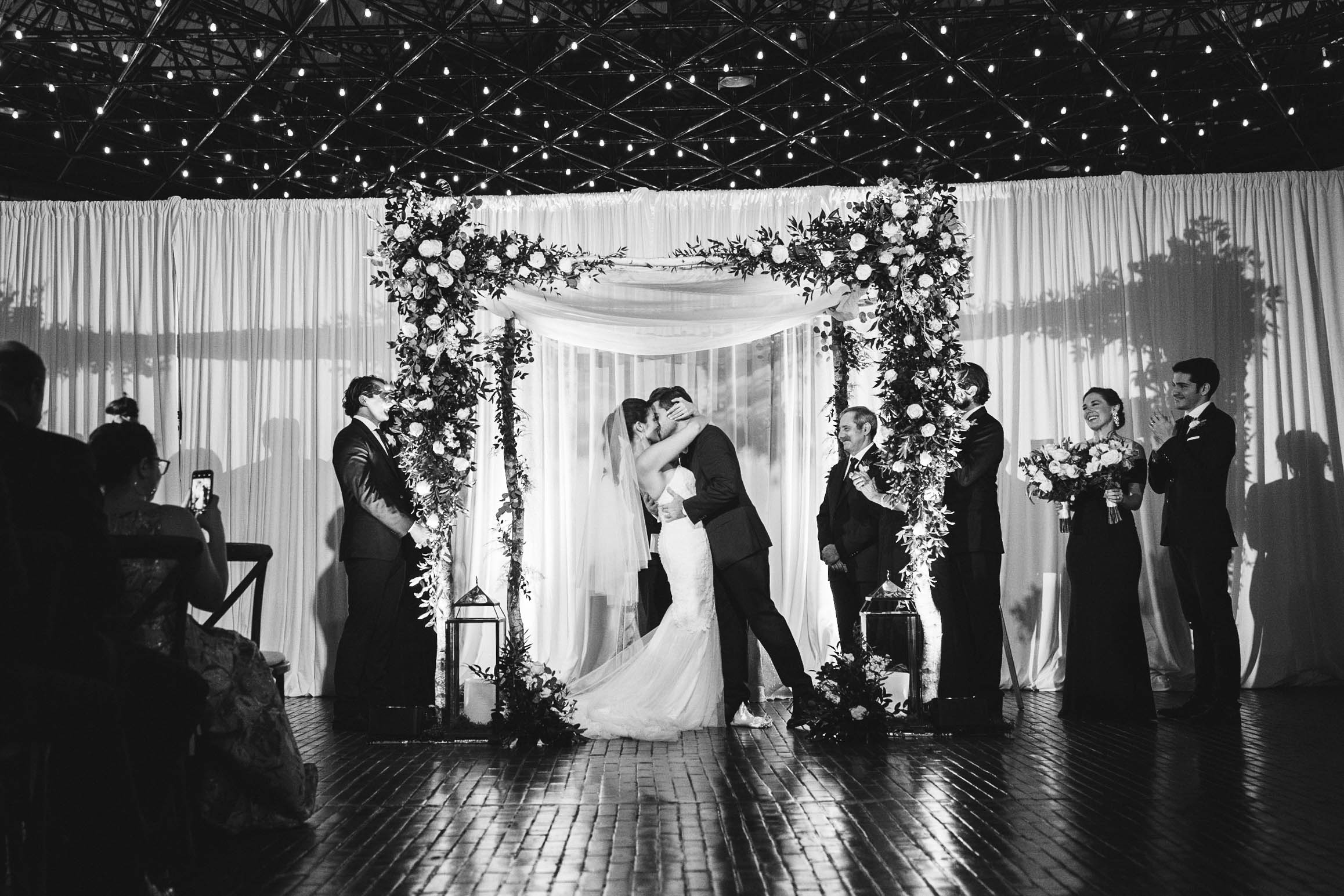 A documentary photograph of a couple kissing during their wedding ceremony at Cyclorama in Boston's South End