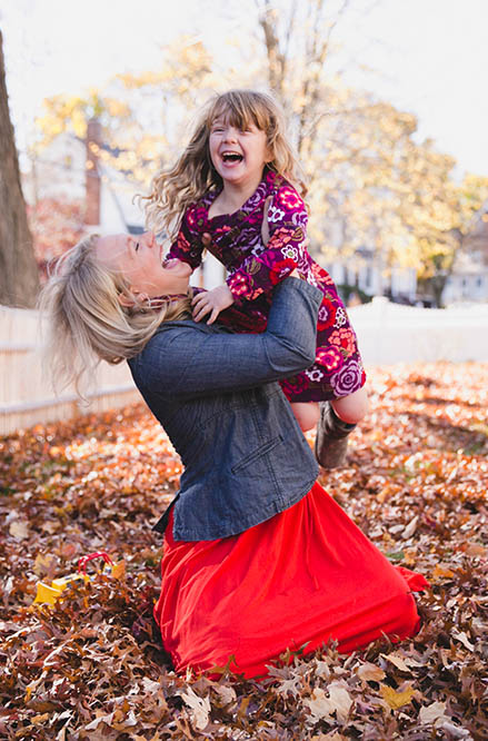 A documentary photograph of a mom playing with her daughter in the yard during an in home family session in Boston