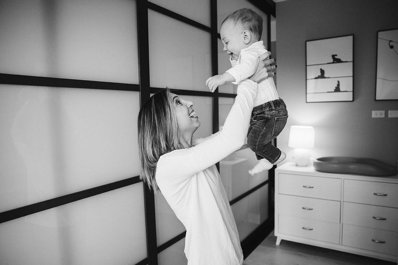 A documentary photograph of a mom playing with her baby during an in home family session in Boston