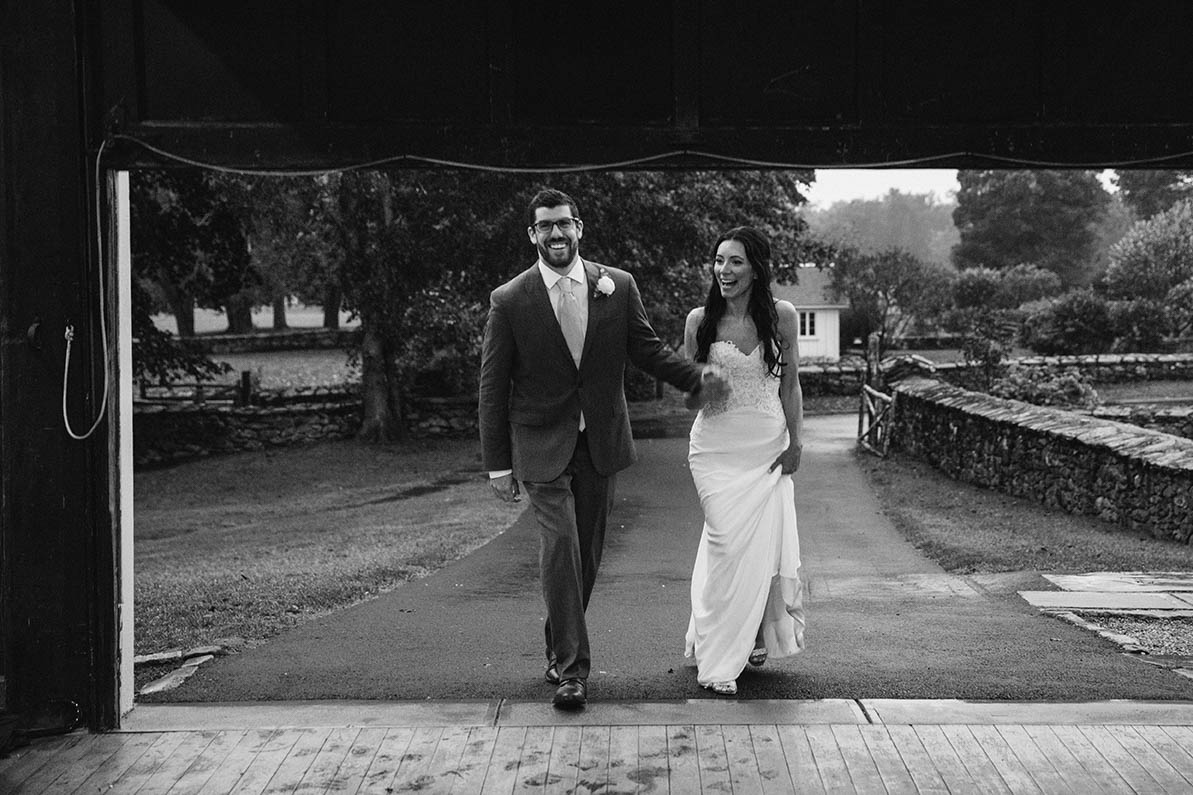 A documentary photograph of a bride and groom entering the reception for their wedding at Mount Hope Farm