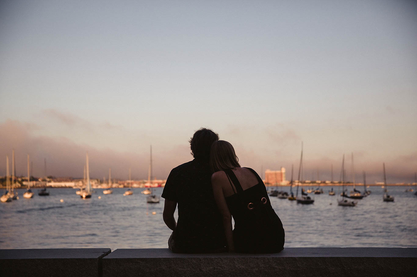A documentary portrait of a couple watching the sunset at the harbor during their Boston engagement session