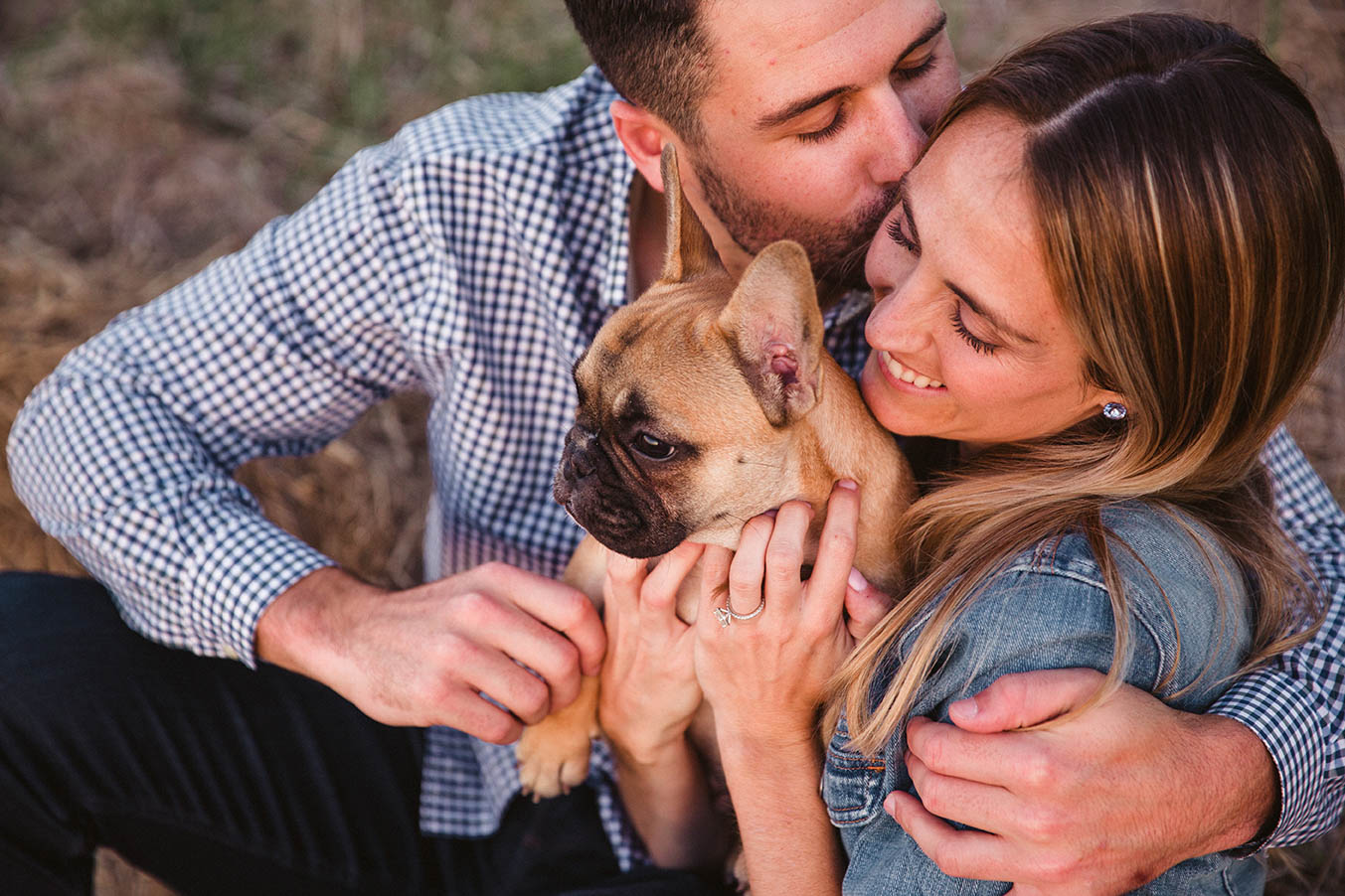 A documentary portrait of a couple snuggling each other and their dog during their Boston engagement session