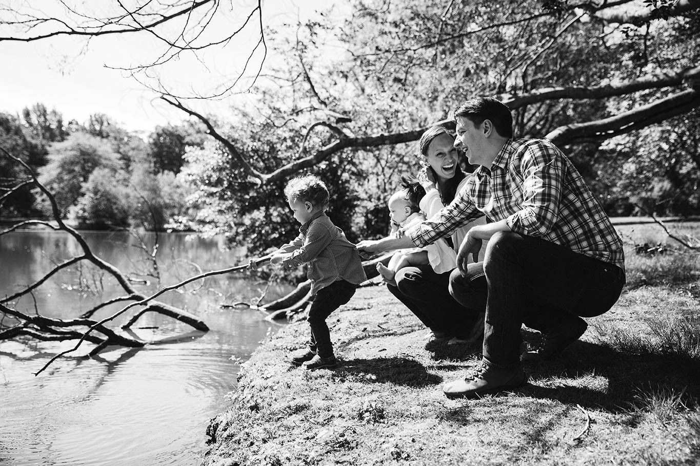 A documentary photograph of a family playing near the water during a Jamaica Plain family session in Boston