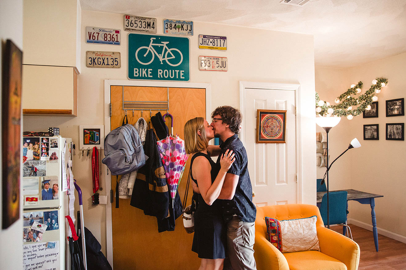 A documentary portrait of a couple kissing eachother at the door of their home during their Boston engagement session