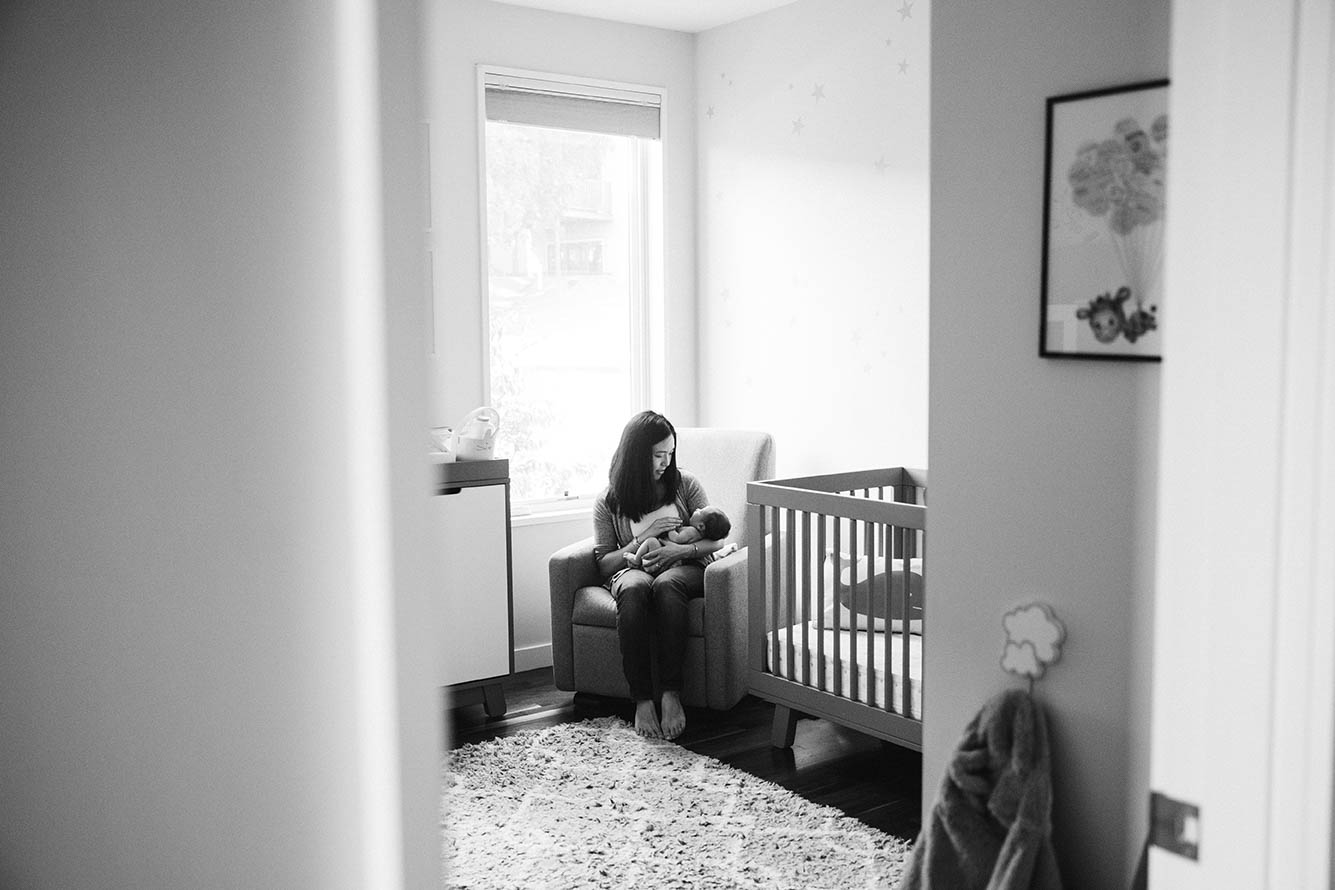 A documentary photograph of mother soothing her newborn baby during an in home newborn session in Boston's Jamaica Plain