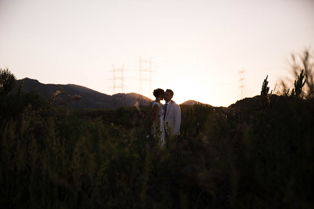 A documentary photograph of a bride and groom kissing during their wedding in the mountains