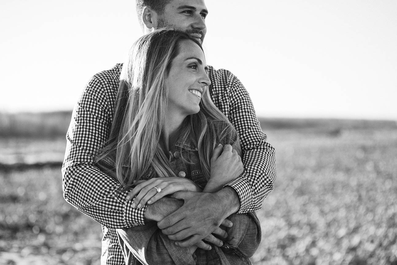 A documentary portrait of a couple hugging at Duxbury Beach during their Boston engagement session