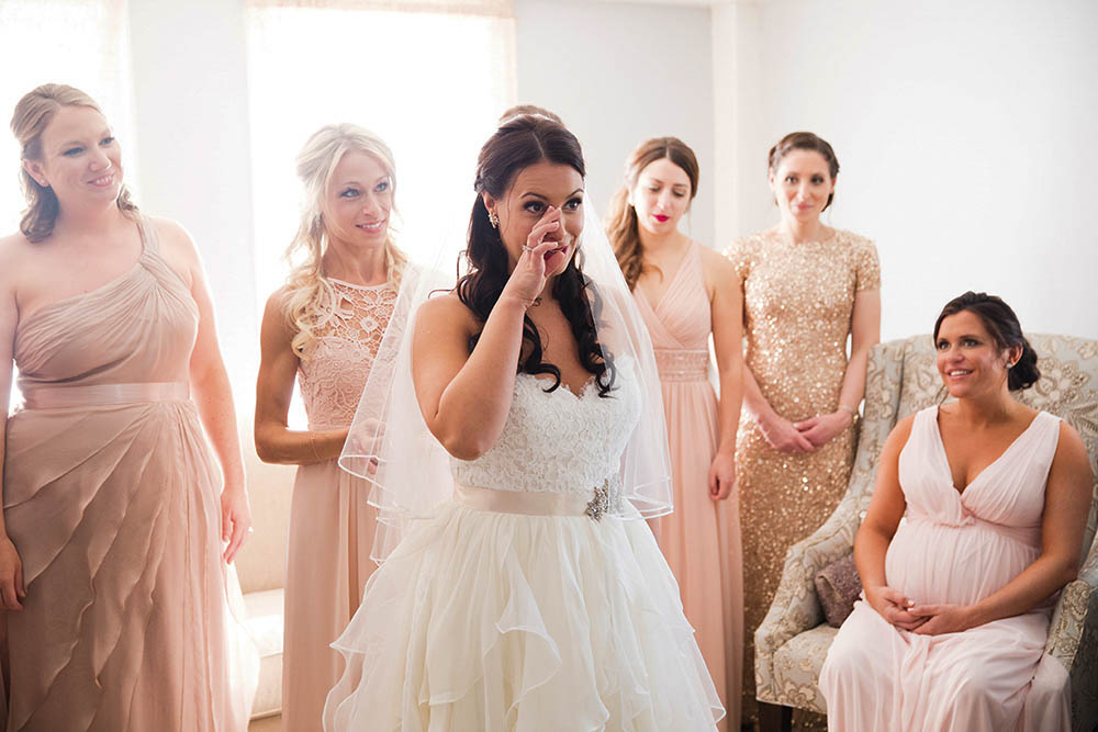 A documentary photograph of bride wiping away a tear as she gets ready for her wedding at Harrington Farm outside of Boston