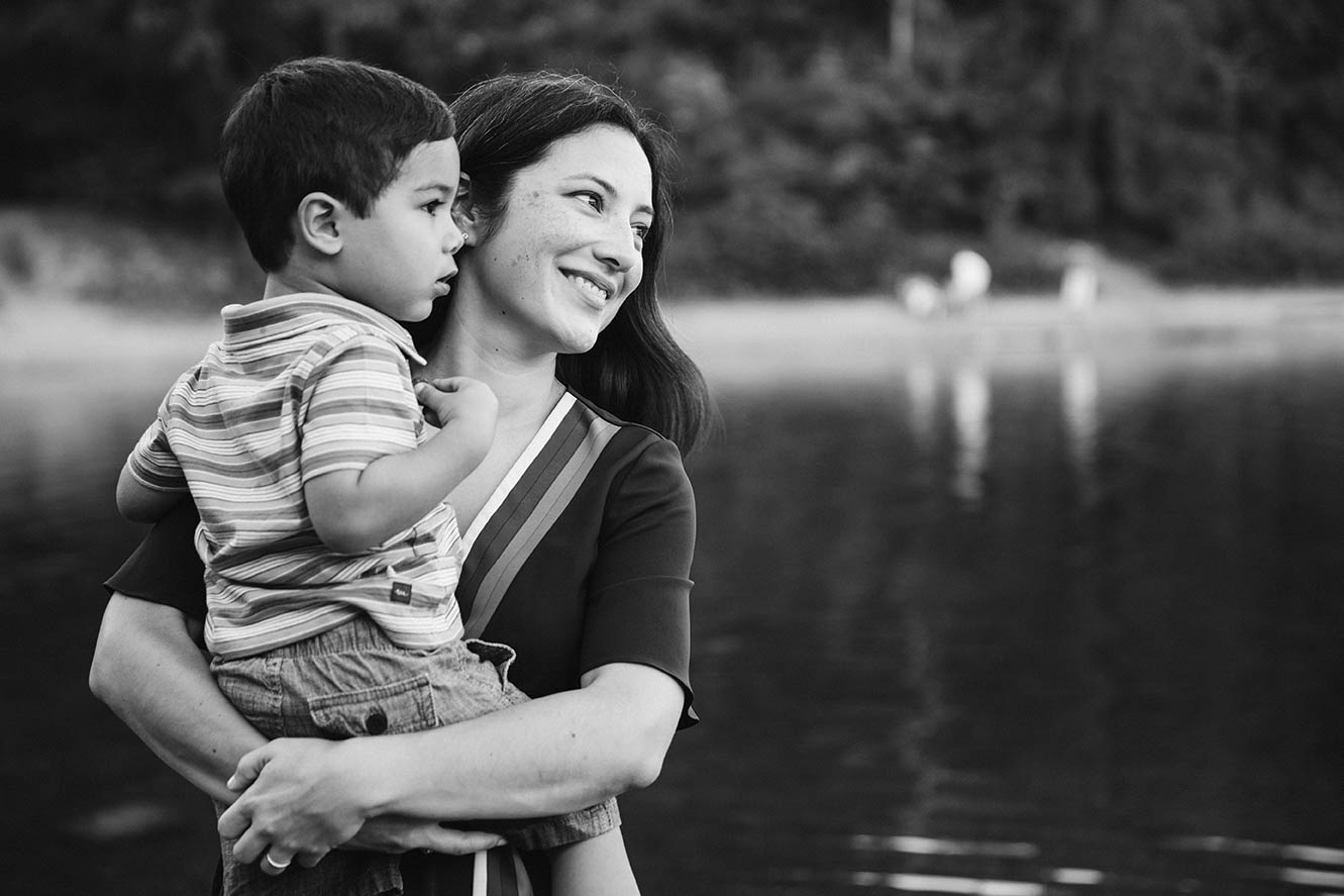 A documentary photograph of a mom holding her toddler during a family session at Walden pond outside of Boston