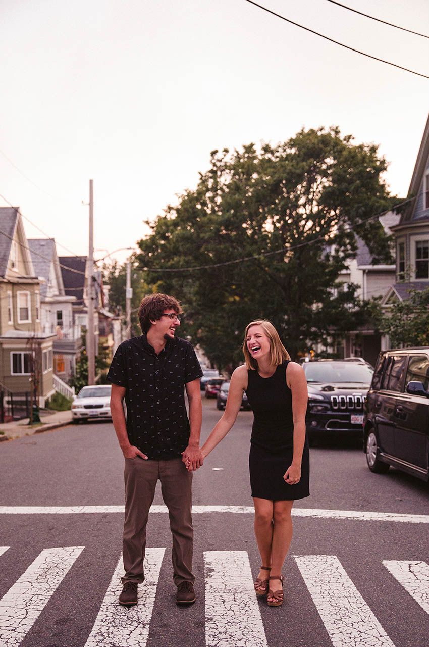 A documentary portrait of a couple laughing in the street during their Boston engagement session