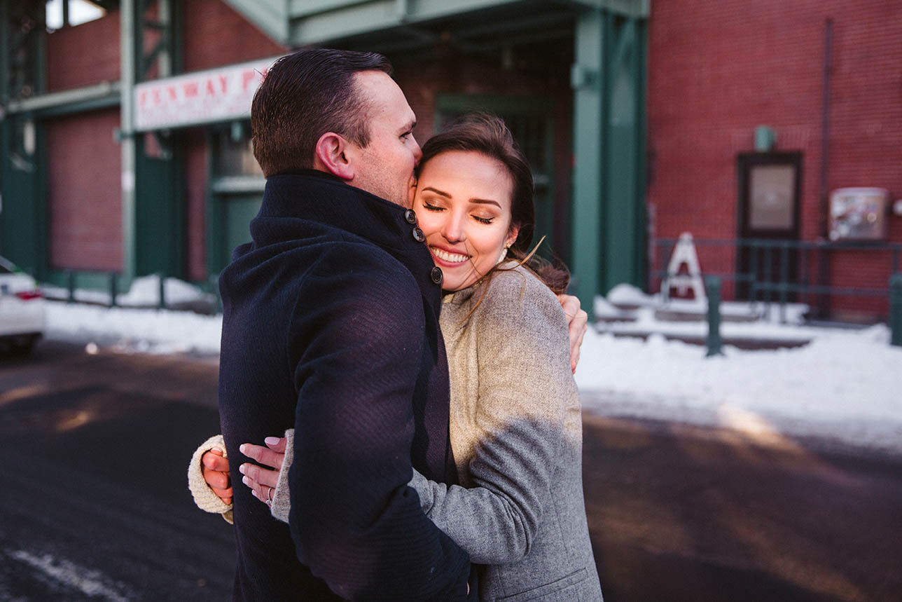 A documentary portrait of a couple hugging at Fenway Park during their Boston engagement session