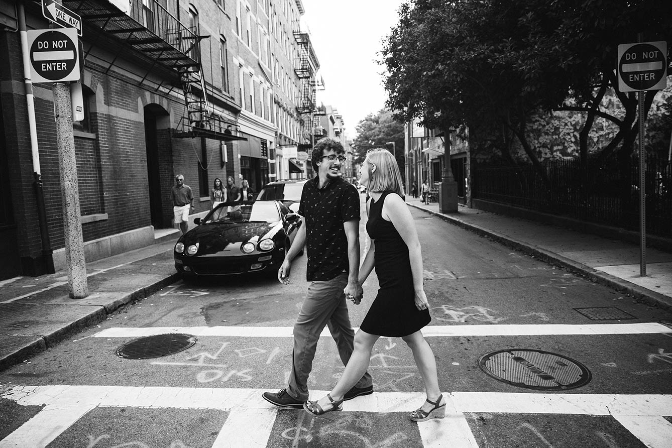 A documentary portrait of a couple crossing the street together during their Boston engagement session