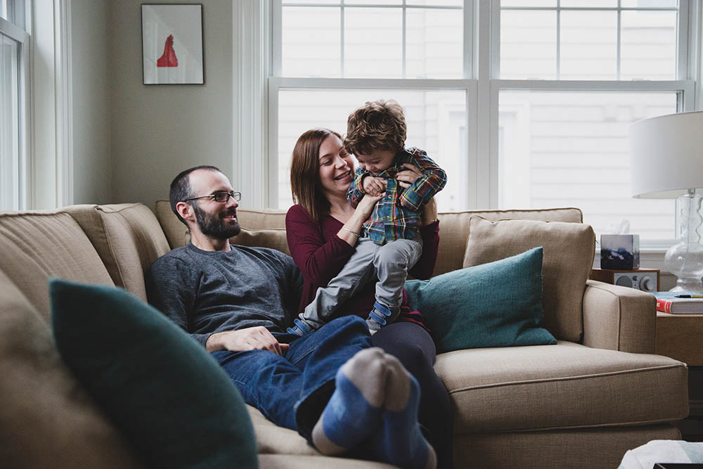 A documentary photograph of a family hangin out on their couch during an in home family session in Boston