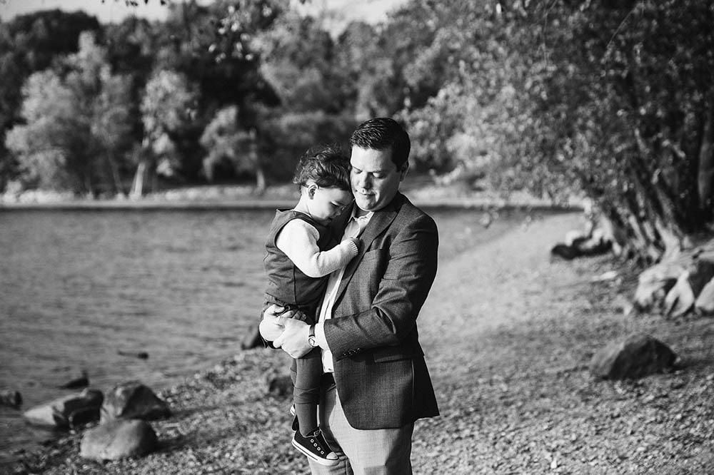 A documentary photograph of a father holding his son during a family session at Jamaica Pond