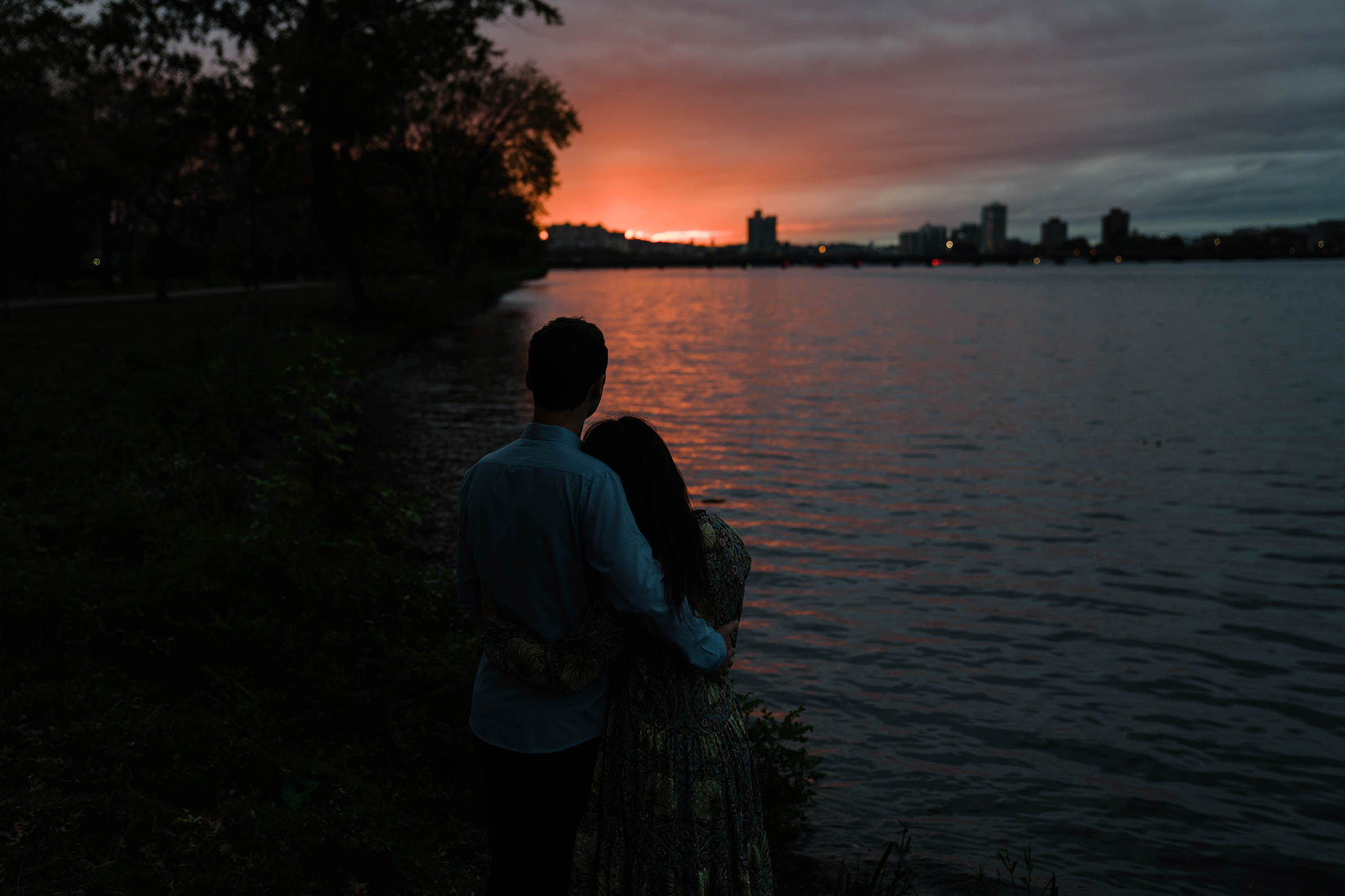 A documentary portrait of a couple watching the sunset from the Charles River Esplande during their Boston engagement session