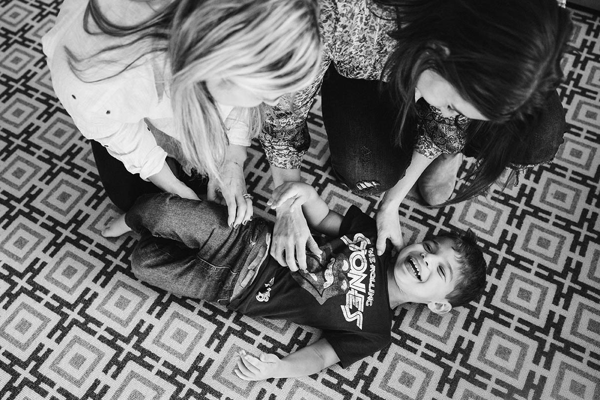 A documentary photograph of a family playing in the living room during their in home family session in Boston