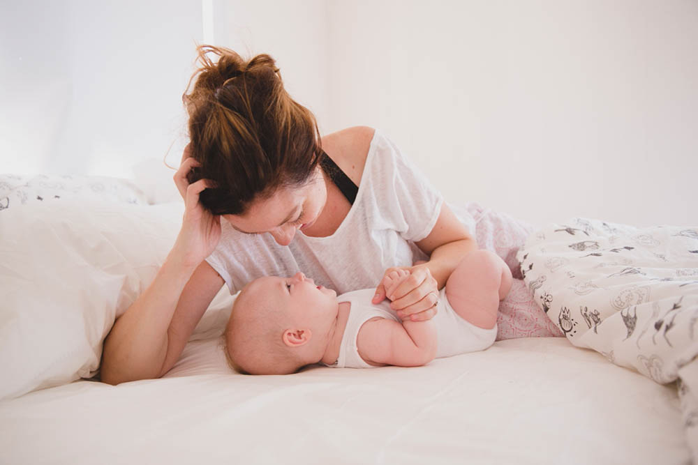 A documentary photograph of a mom cuddling with her daughter during their in home family session in Boston