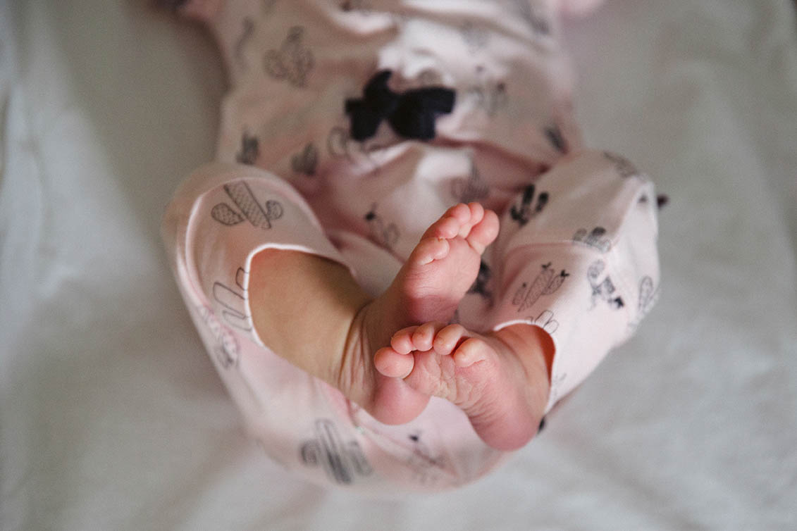 A documentary photograph of a newborn stretching her feet during an in home family session in Boston