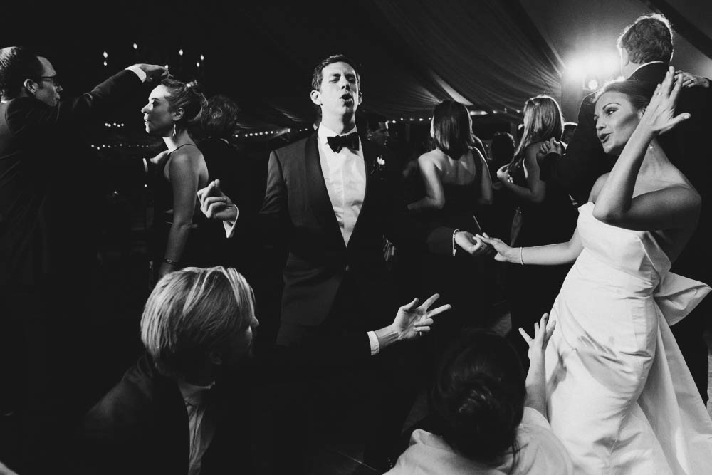 A documentary photograph of a bride and groom dancing with their friends during a Castle Hill Inn wedding