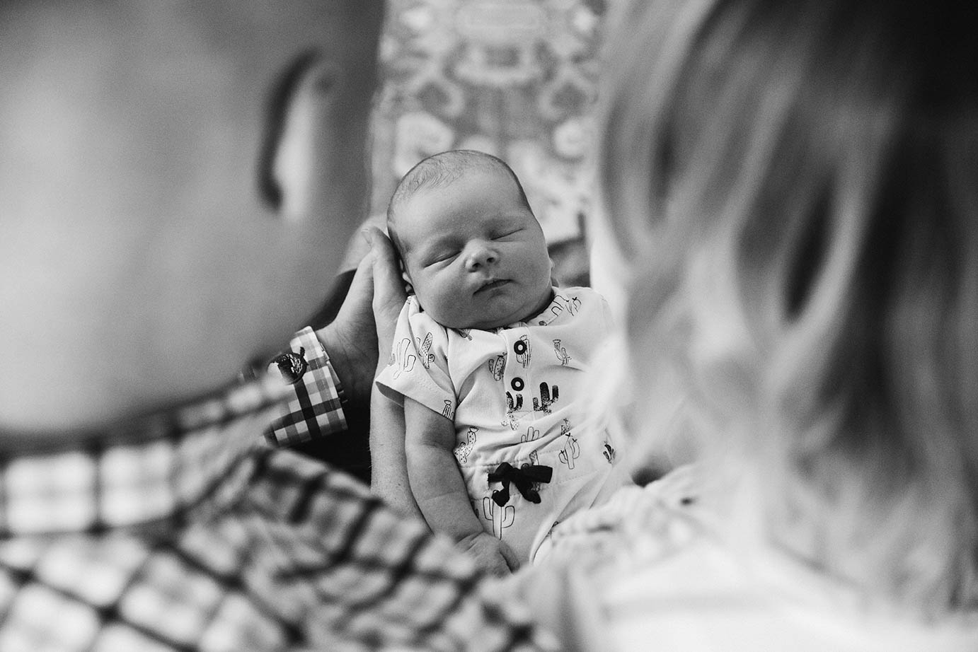 A documentary photograph of two parents looking at their newborn daughter during an in home family session in Boston