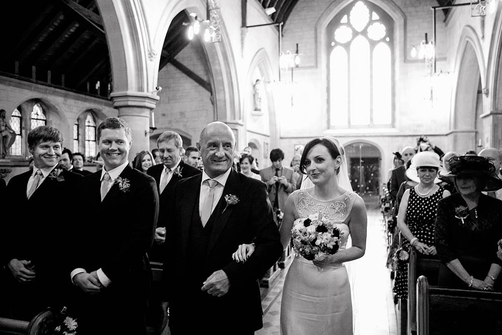 A documentary photograph of a bride walking down the aisle during her Boston wedding