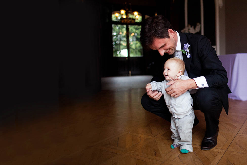 A documentary photograph of a father helping his son dance during a Boston wedding