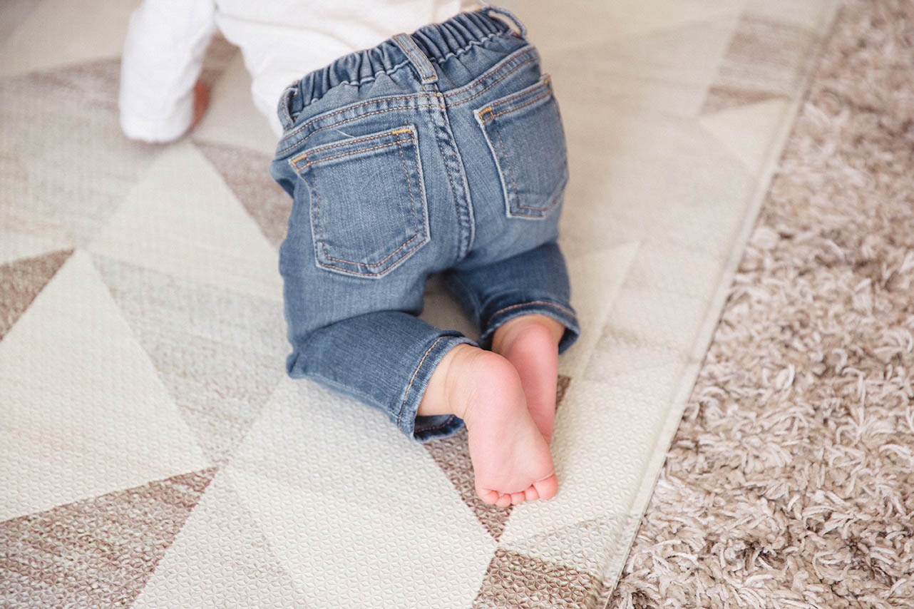 A documentary photograph of a baby crawling on the ground during an in home family session in Boston