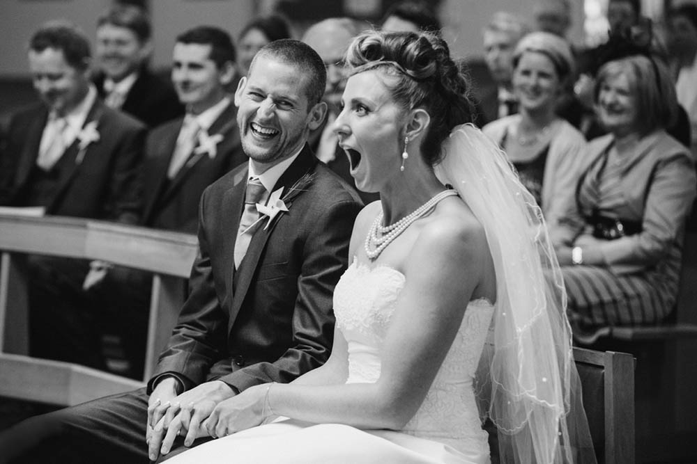 A documentary photograph of a bride and laughing during their Boston wedding ceremony