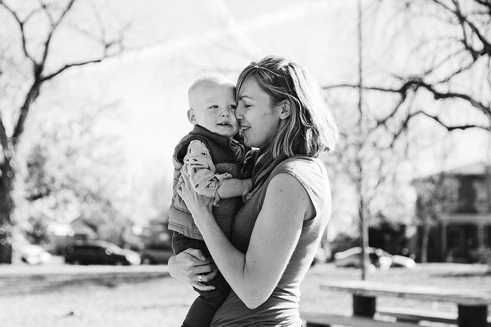 A documentary photograph of a mother holding and cuddling her son during their outdoor family session
