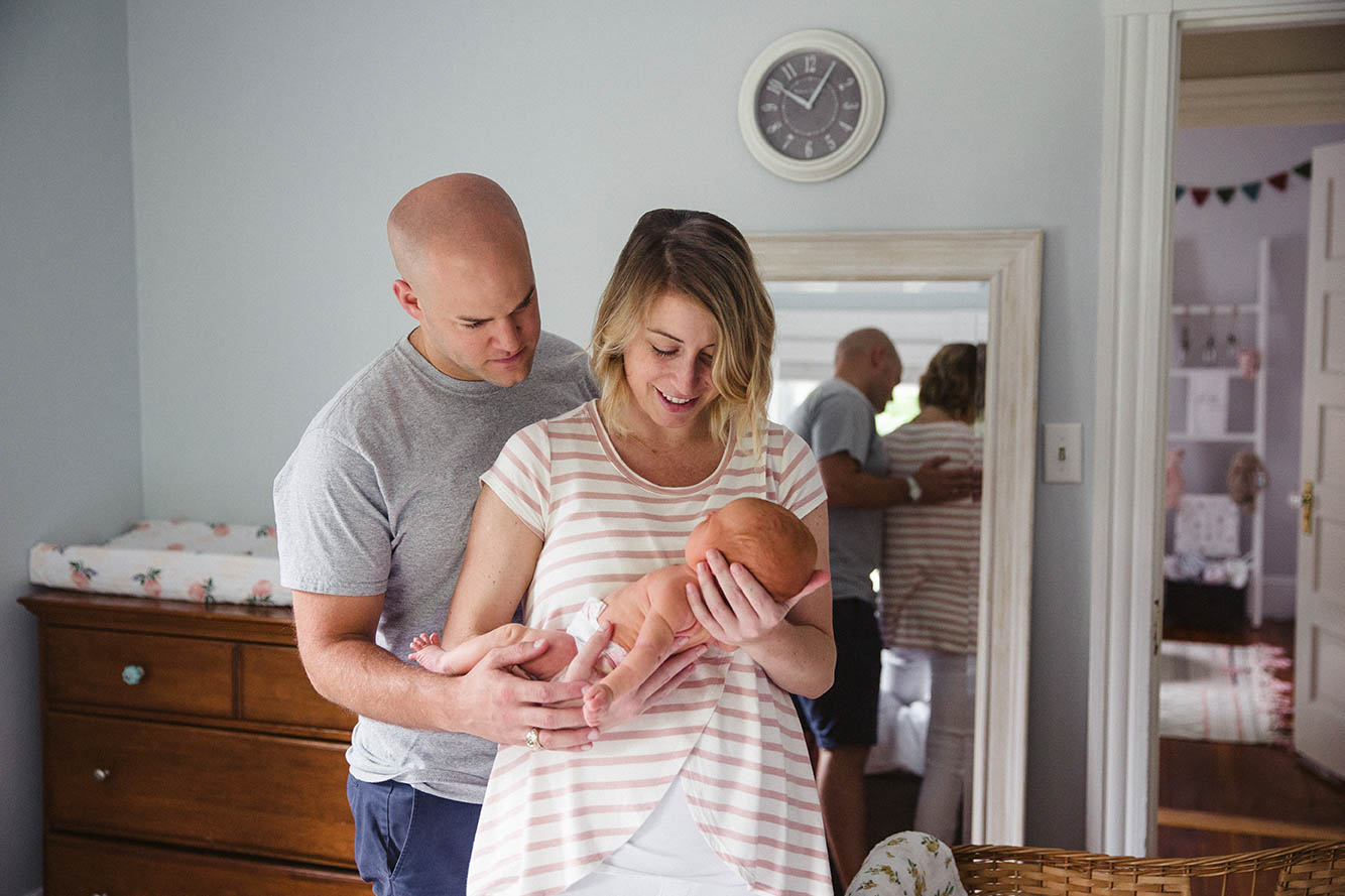 A documentary photograph of parents with their newborn daughter during an in home newborn session in Boston