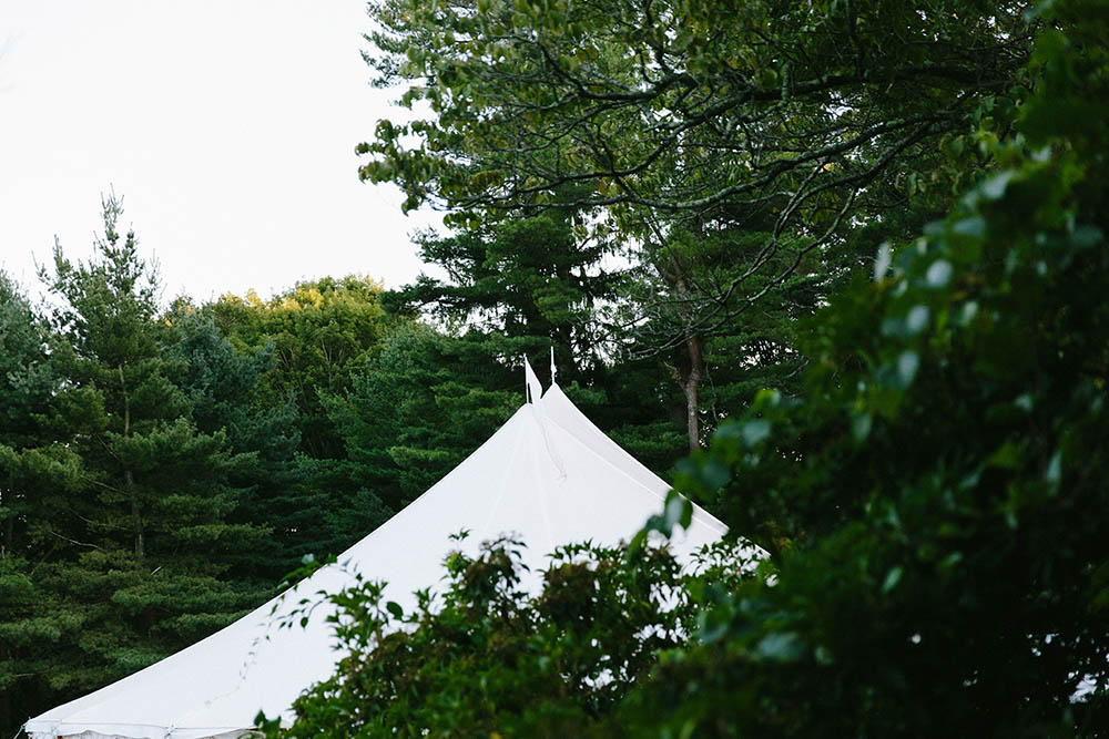 A documentary photograph of a wedding tent in the trees during a Boston wedding