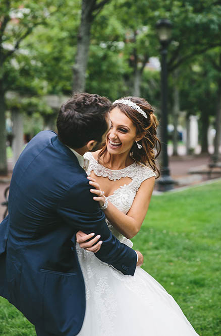 A documentary photograph of a bride and groom laughing during their portrait session at the Boston Public Gardens before their State Room wedding