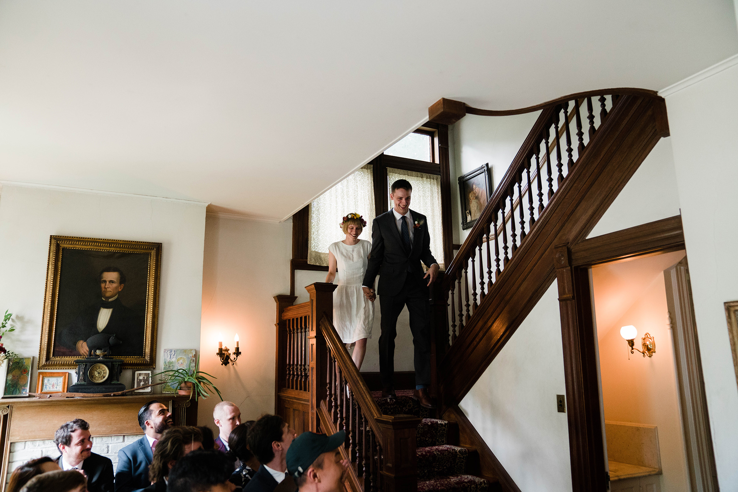 A documentary photograph featured in the best of wedding photography of 2019 showing a couple walking down the stairs to their in home wedding ceremony