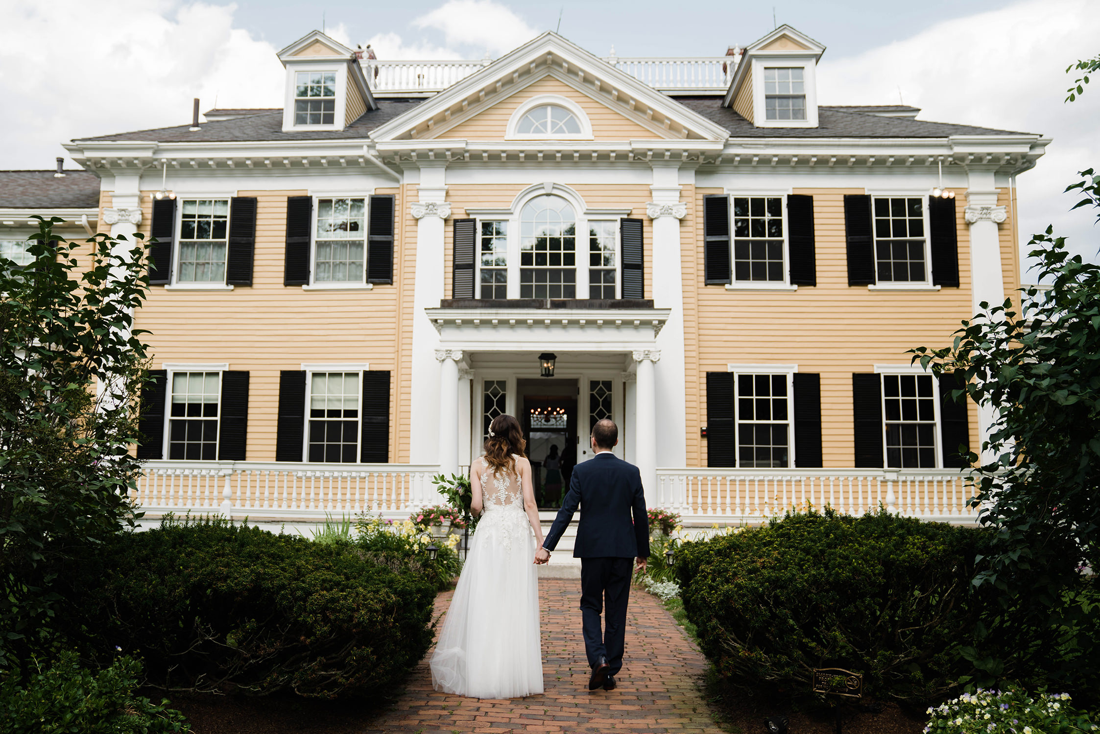 A documentary photograph featured in the best of wedding photography of 2019 showing a couple walking into their wedding reception at Pierce House