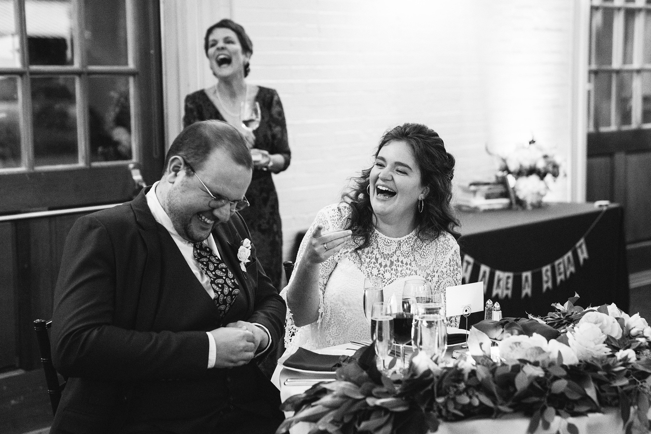 A documentary photograph featured in the best of wedding photography of 2019 showing a bride and groom laughing during their wedding toasts