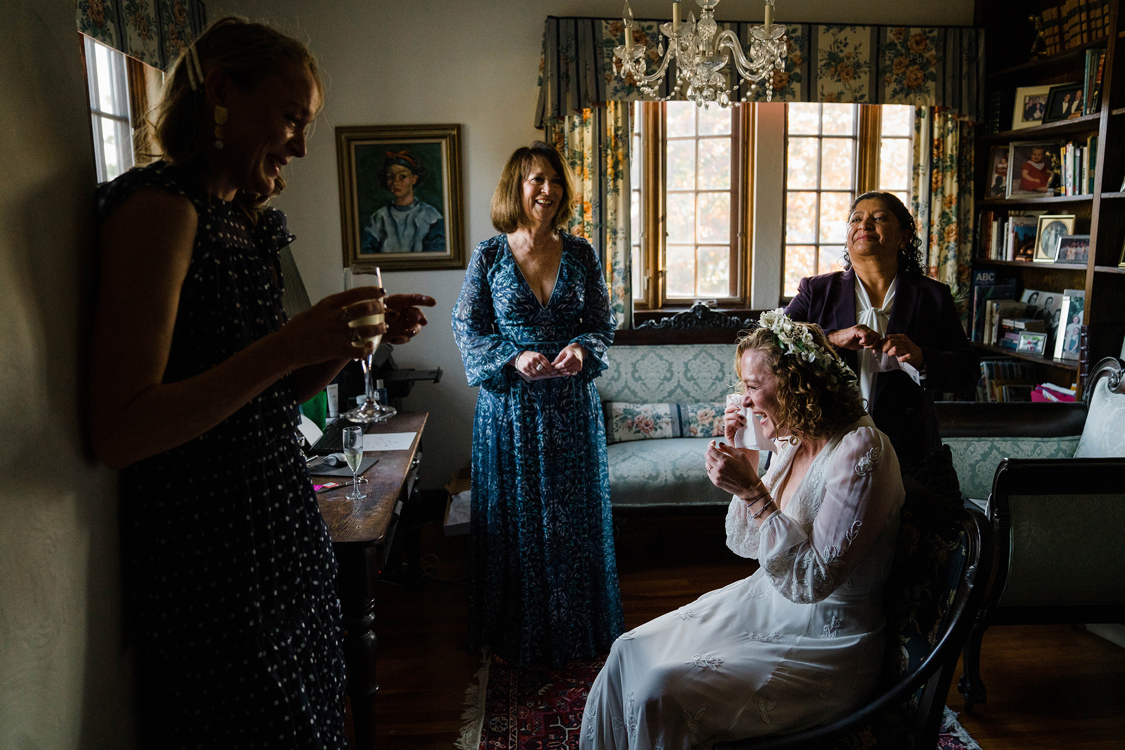 A documentary photograph featured in the best of wedding photography of 2019 showing a bride crying and laughing while getting ready at home with family and friends