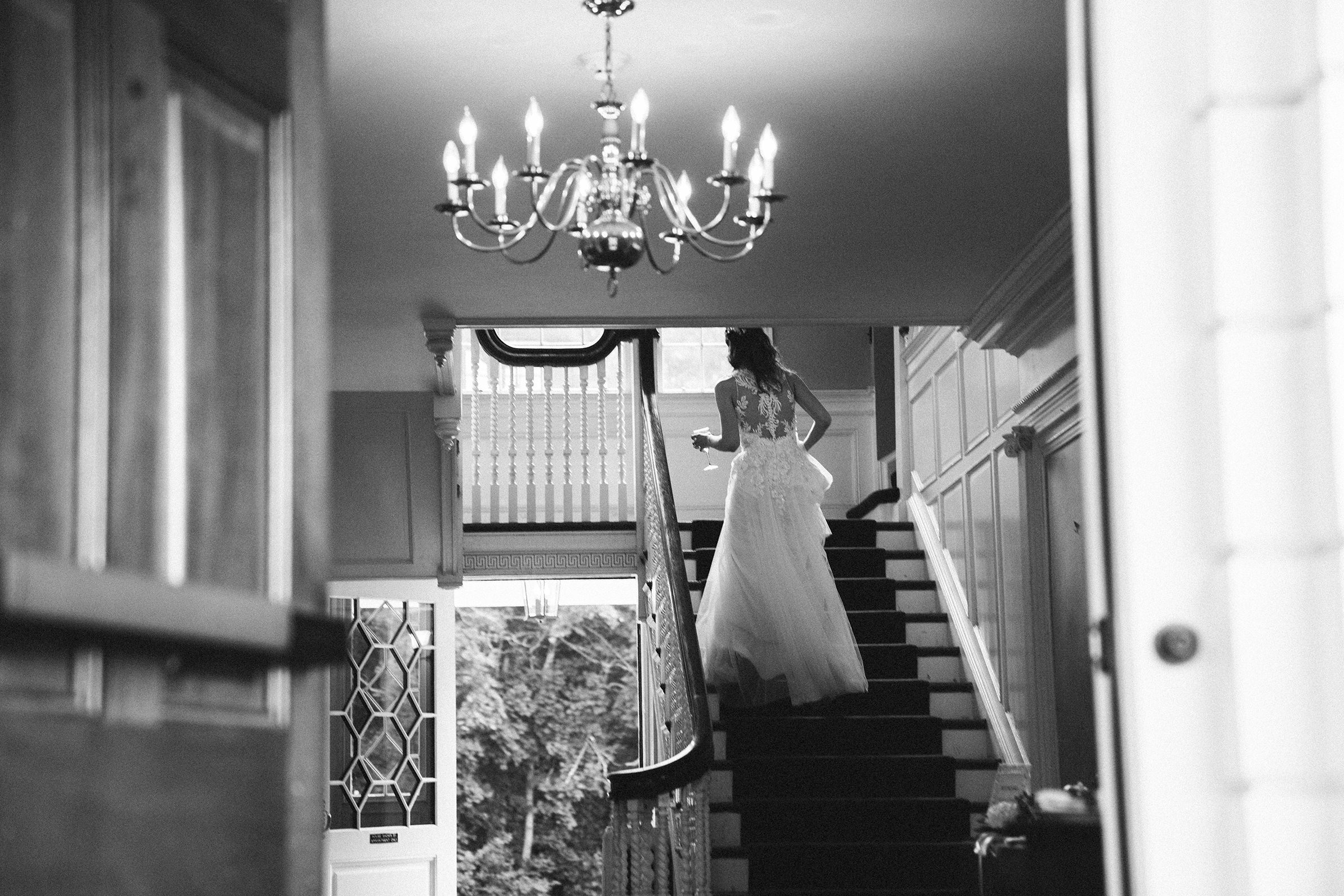 A documentary photograph featured in the best of wedding photography of 2019 showing a bride walking up the stairs at Pierce House