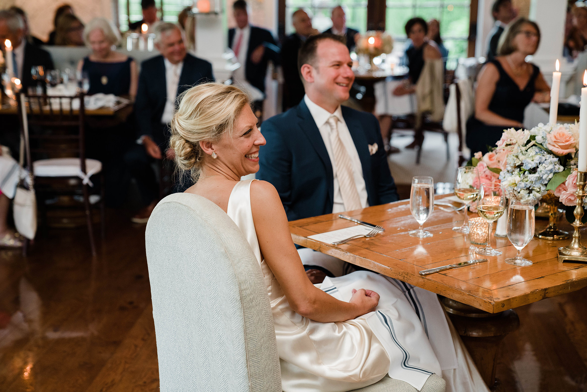 A documentary photograph featured in the best of wedding photography of 2019 showing a bride and groom laughing during the wedding toasts