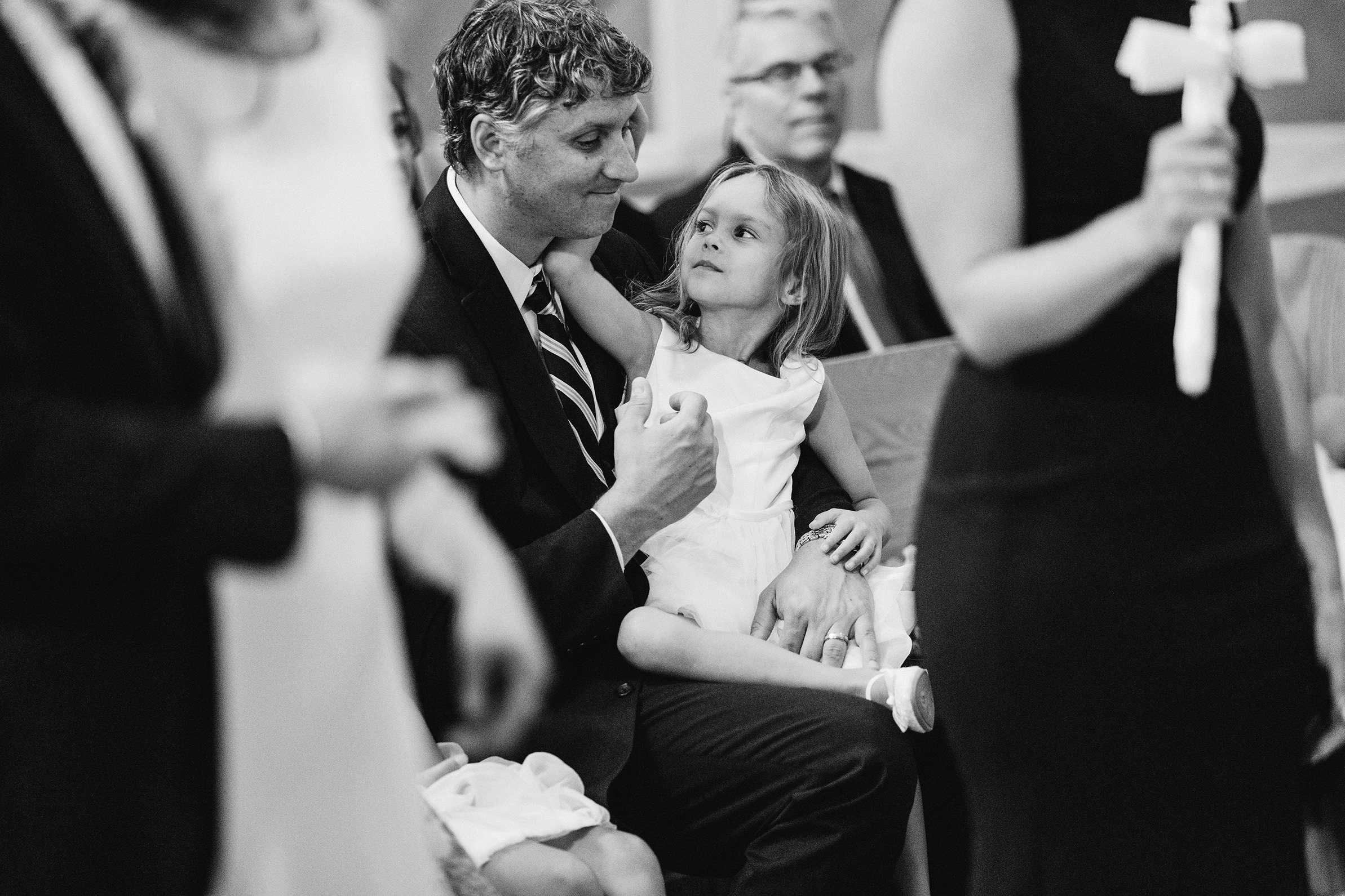 A documentary photograph featured in the best of wedding photography of 2019 showing a little girl playing with dad during a wedding ceremony