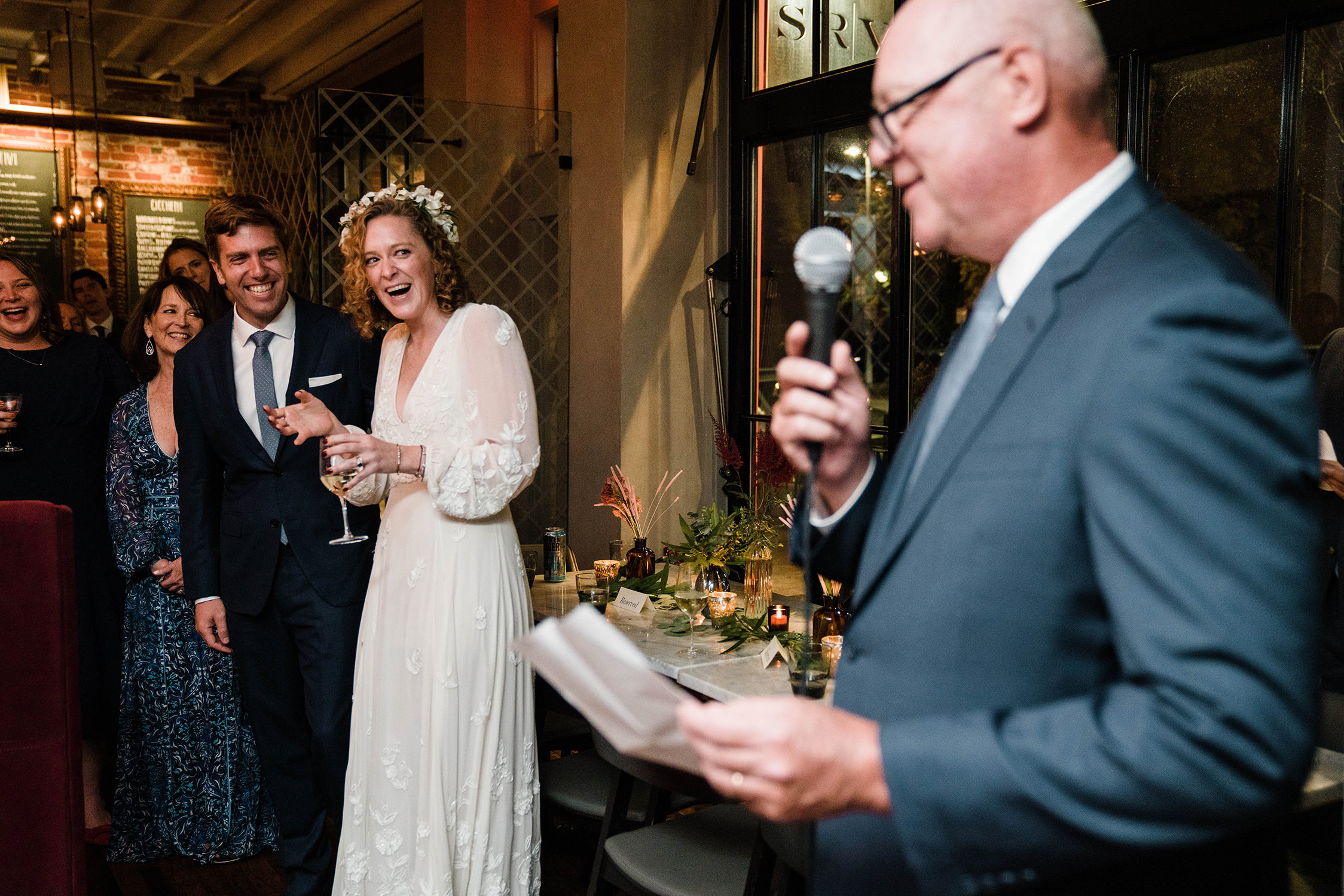 A documentary photograph featured in the best of wedding photography of 2019 showing a bride laughing during her father's toasts