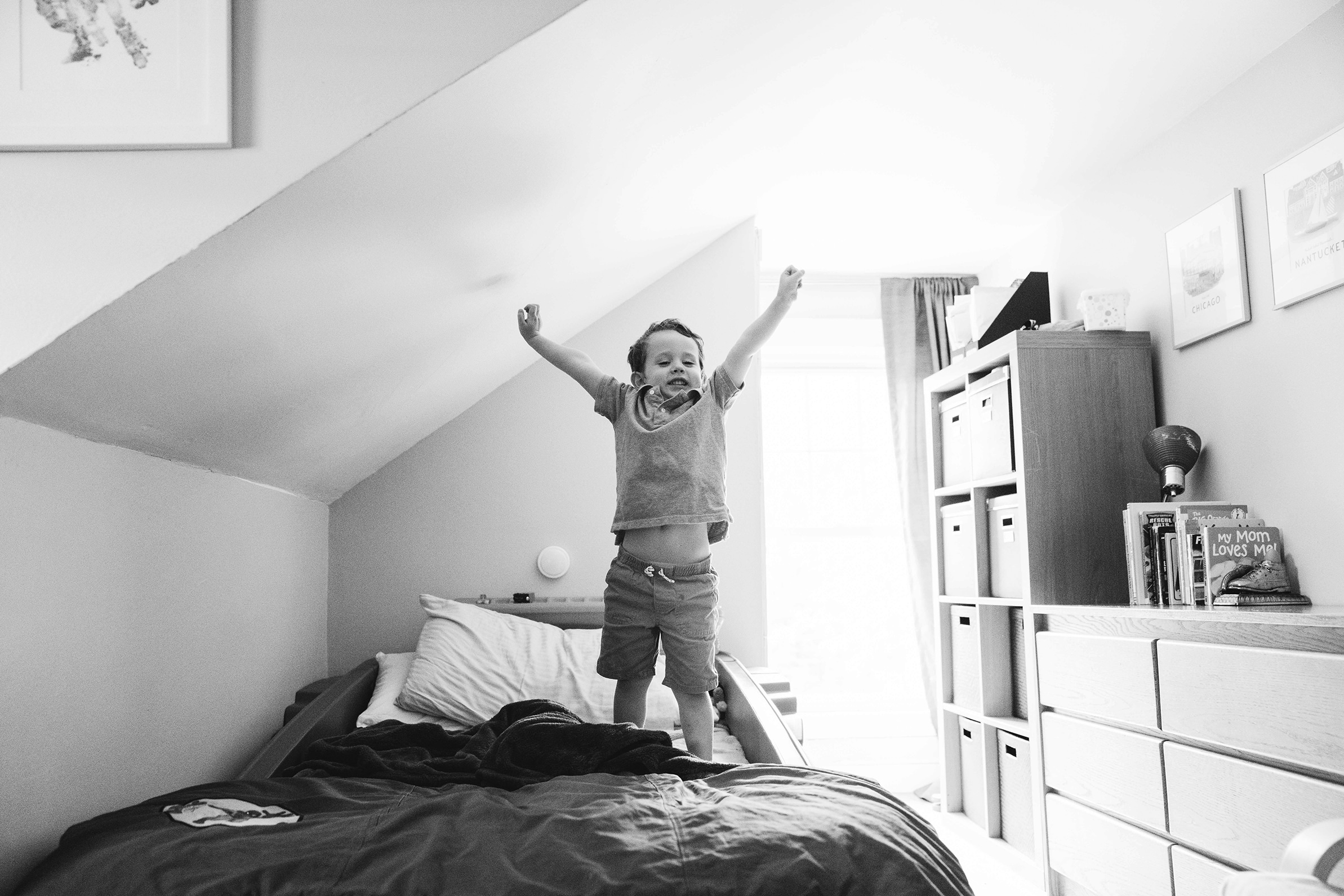 A documentary photograph of a boy stretching on his bed after a nap during his in home family session in Boston