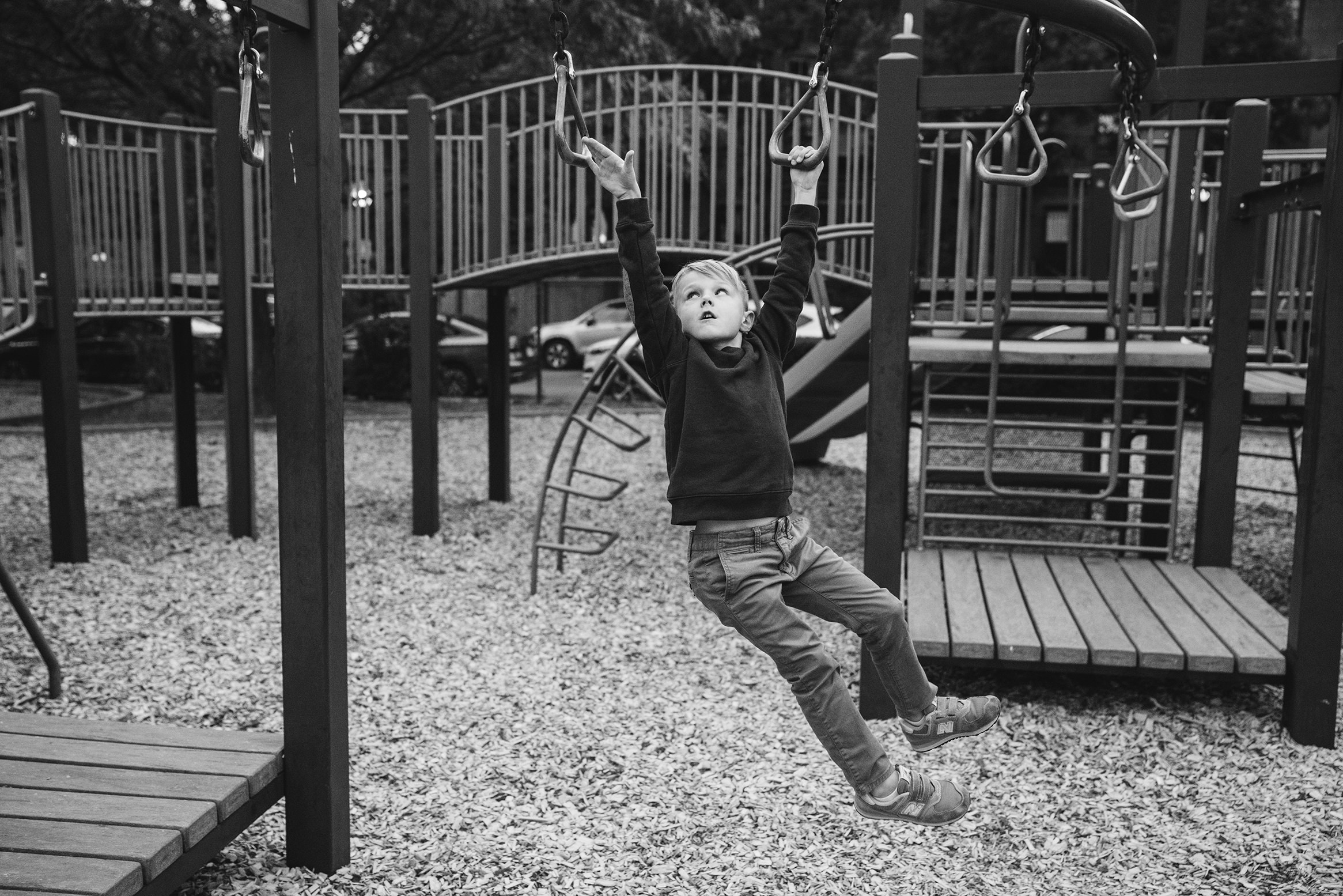 A documentary photograph of a boy playing at the playground during a day in the life family session in Boston