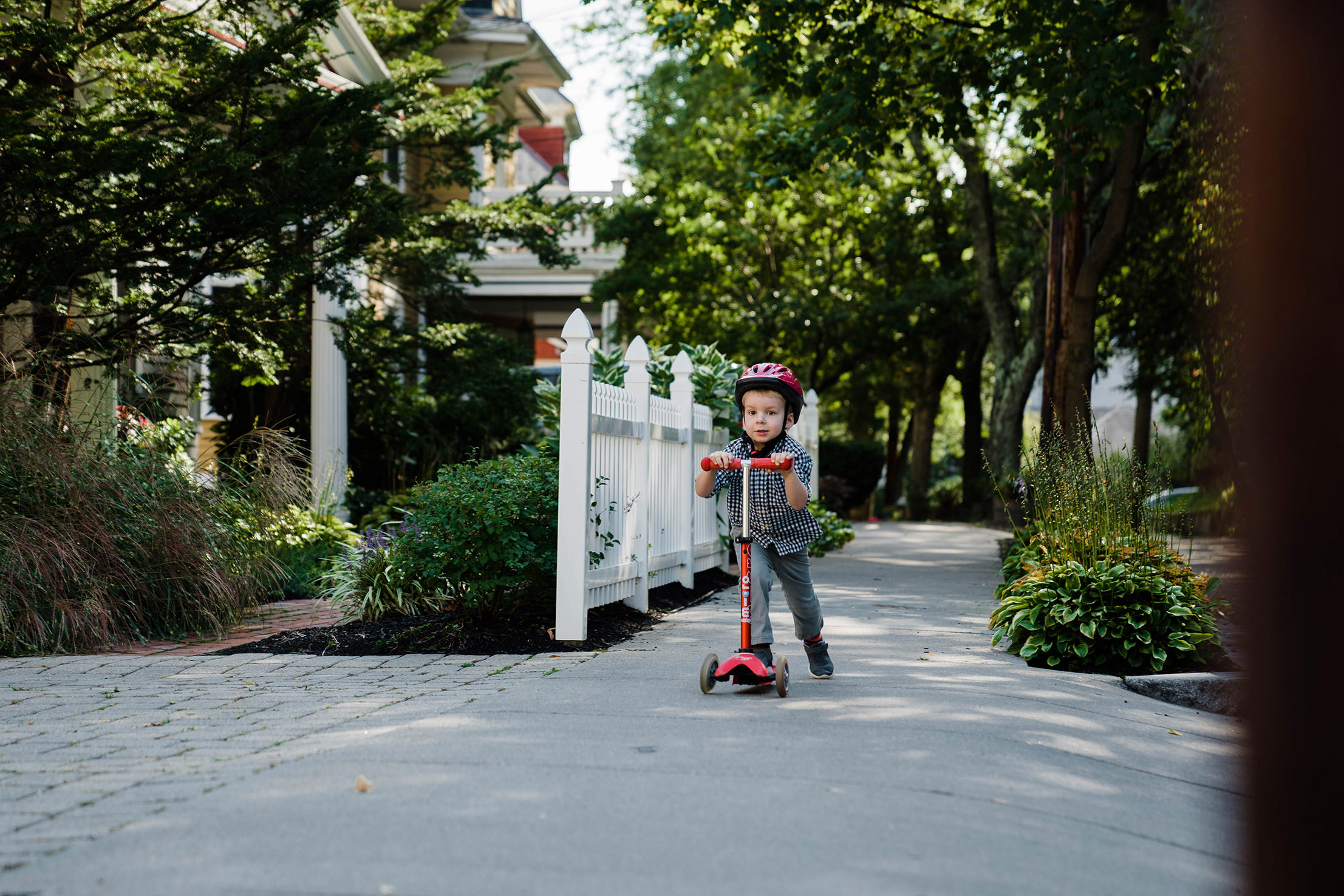 A best of Boston family photograph of boy riding his scooter on the side walk during an in home family session in Boston