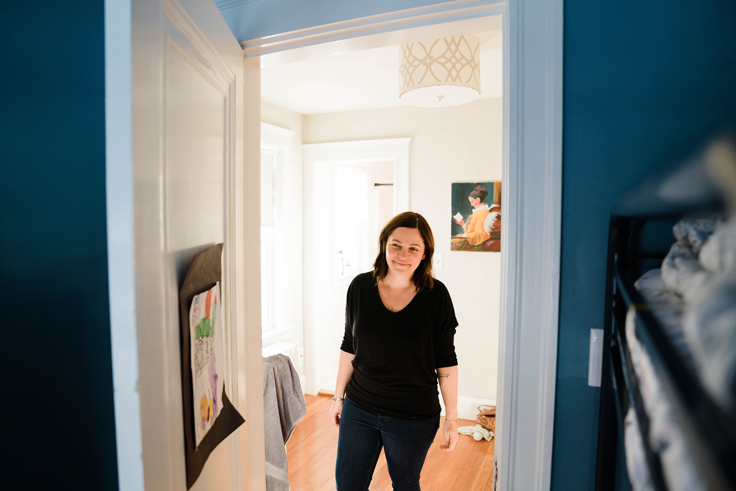 A documentary photograph of a mom watching her son play in his room during an in home family session in Boston