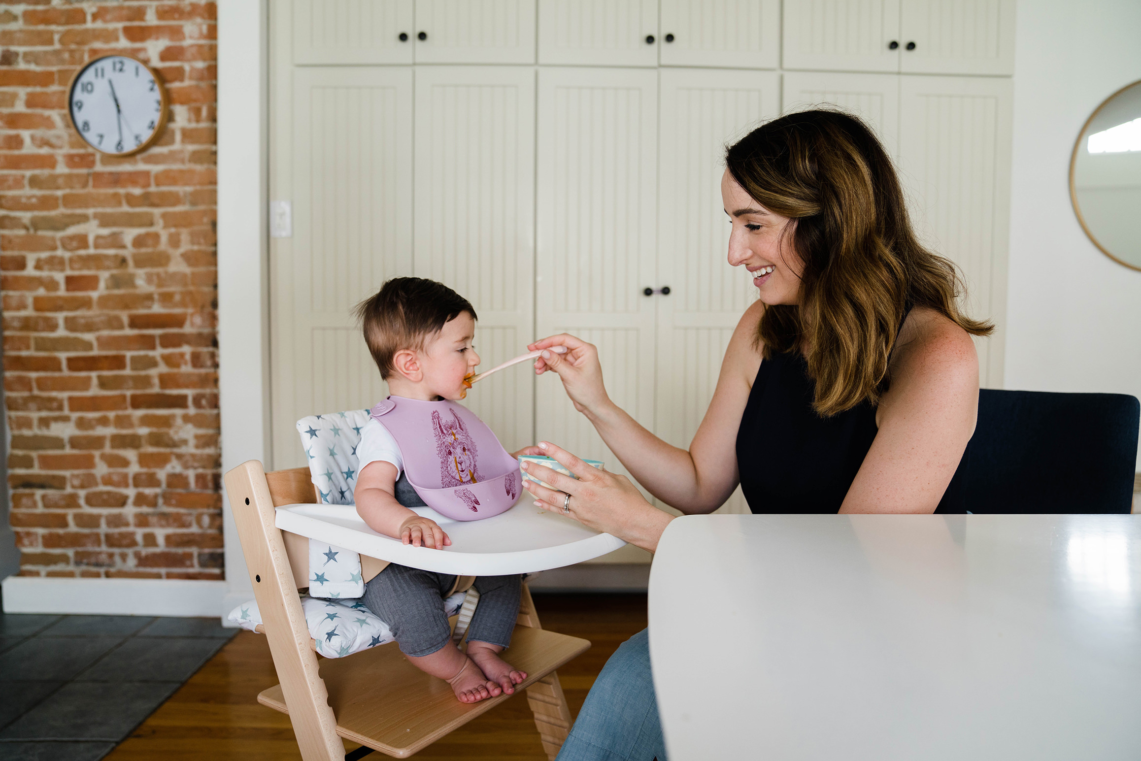 A documentary photograph of mom feeding her son during an in home family session in Boston